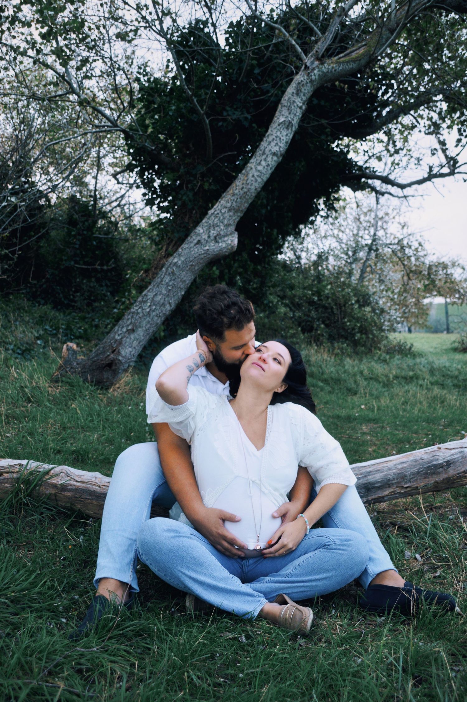 Romantic maternity photos taken in natural outdoor setting with trees.