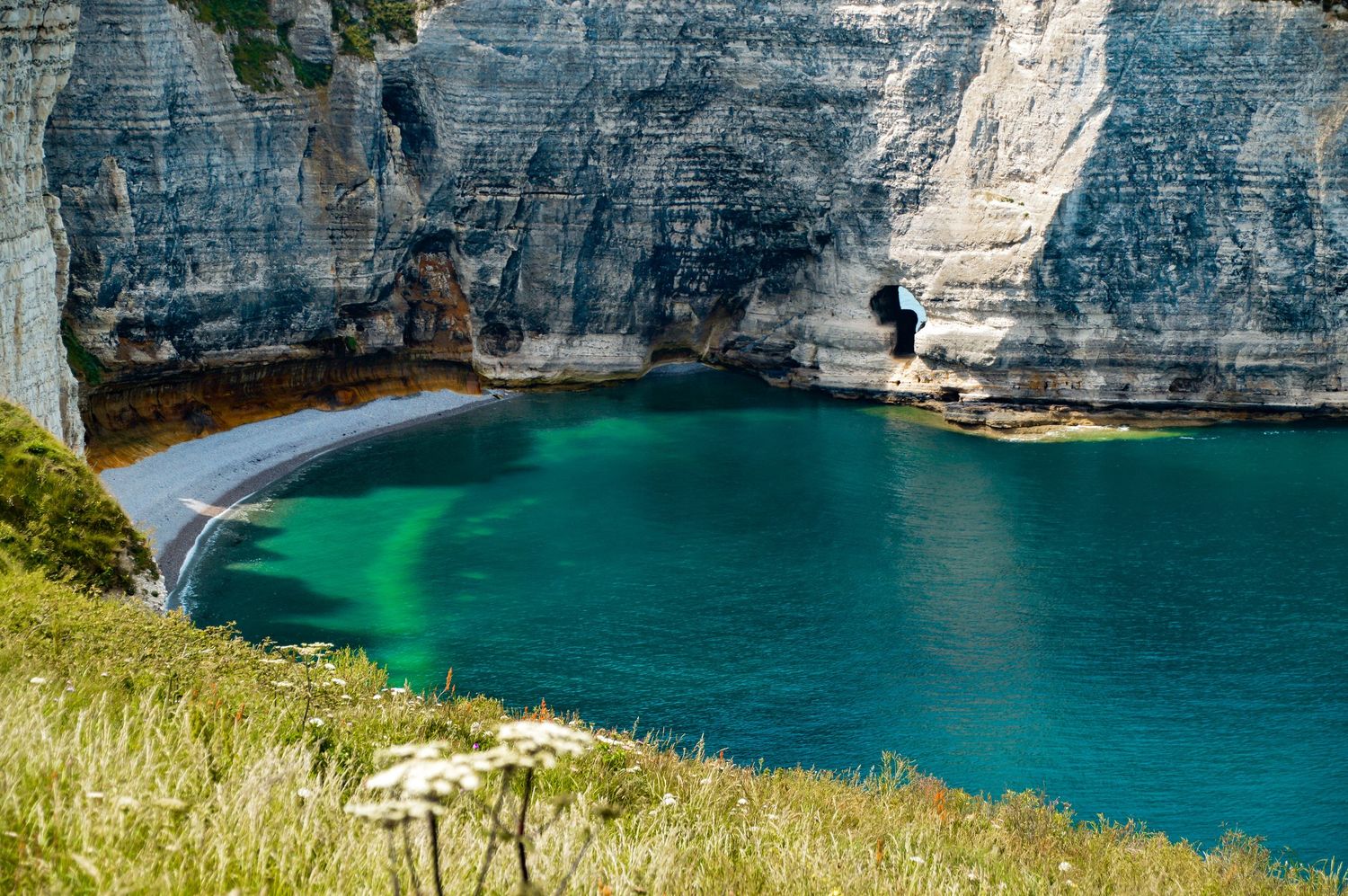 Panoramic view of white chalk cliffs meeting turquoise waters in a coastal bay.