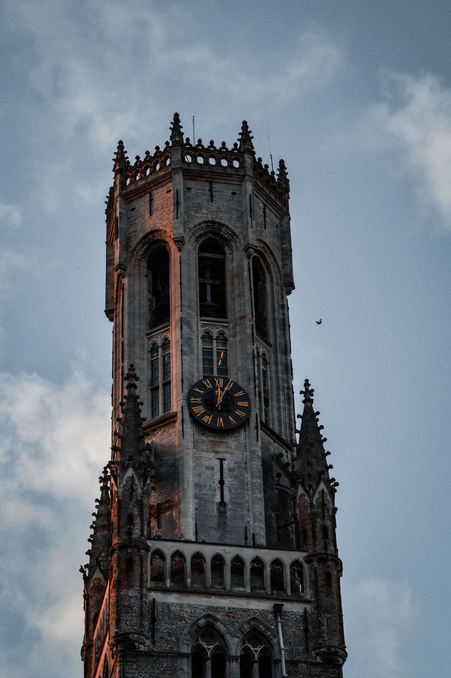 Gothic church tower with ornate architectural details against cloudy sky.