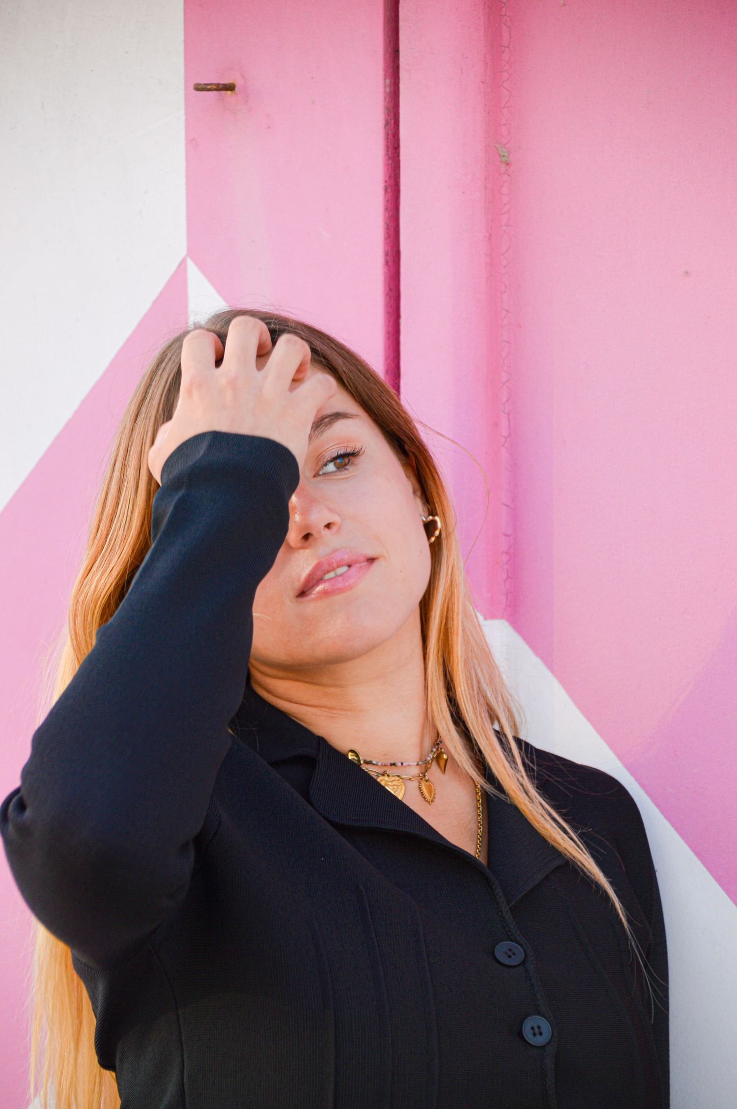 Artistic portrait against pink and white wall showing dramatic angles and shadows.