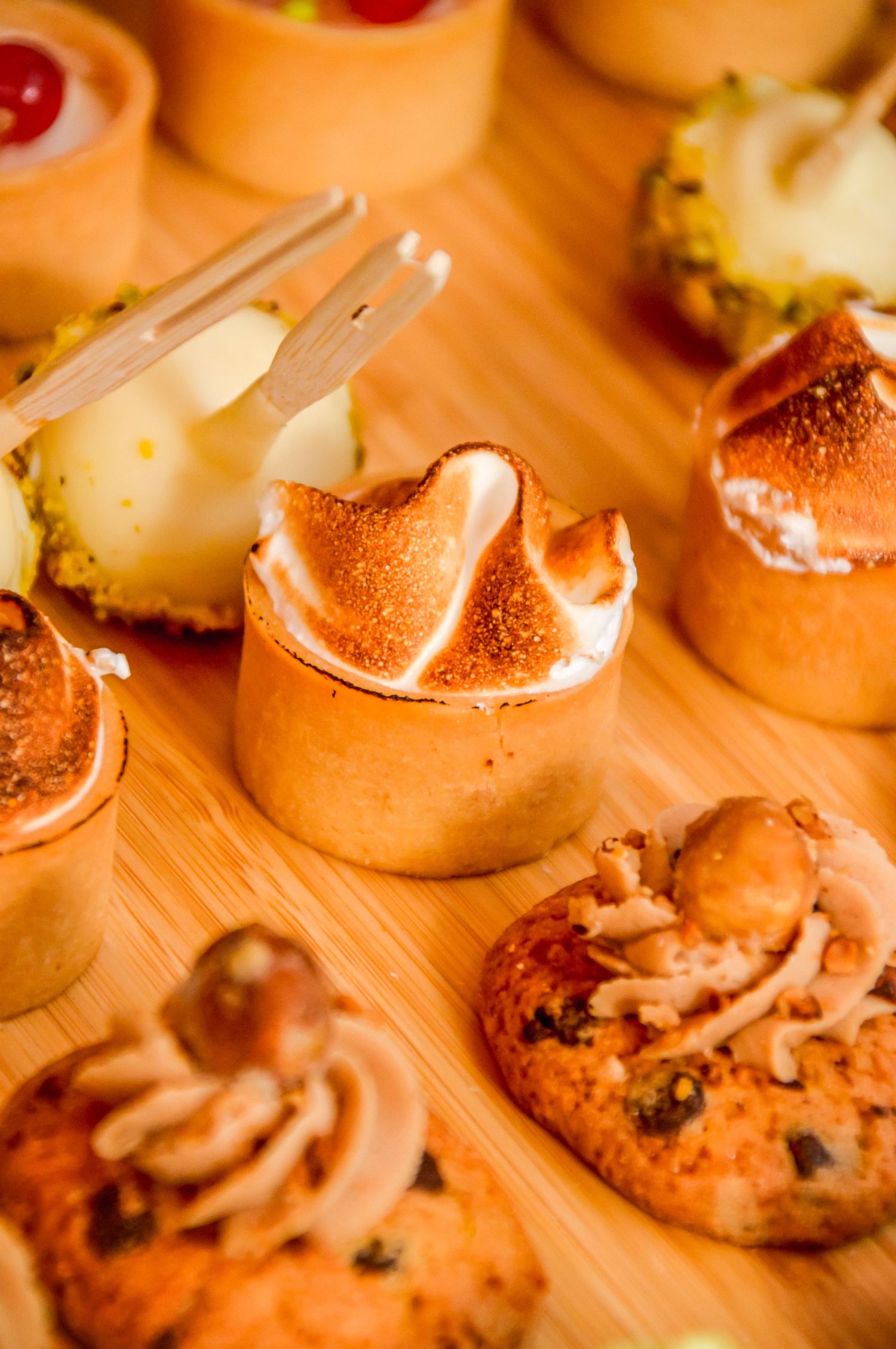Artfully arranged appetizers with cherry garnishes on wooden serving board.