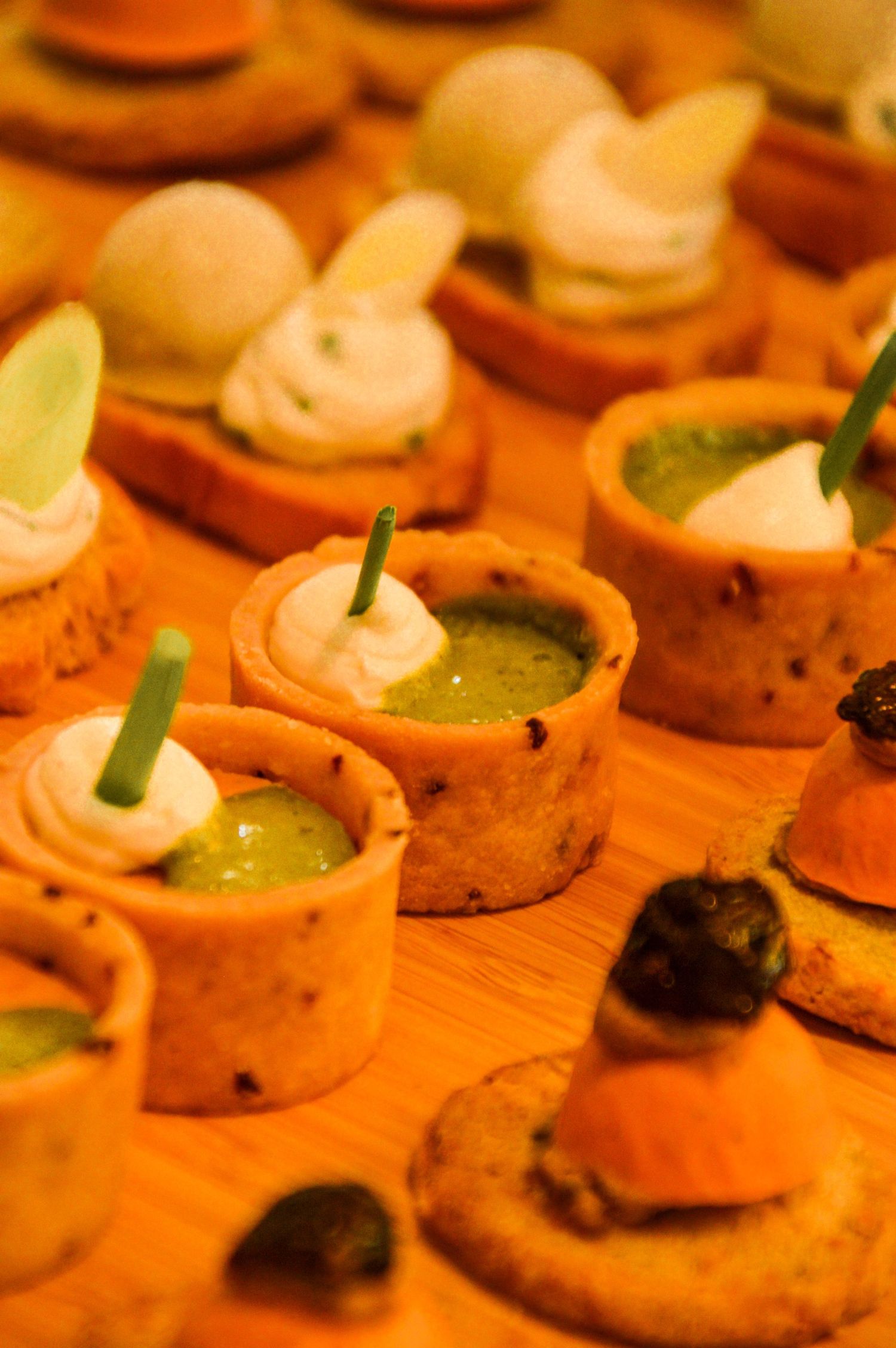 Gourmet appetizers with green sauce and cream toppings served in small cups.