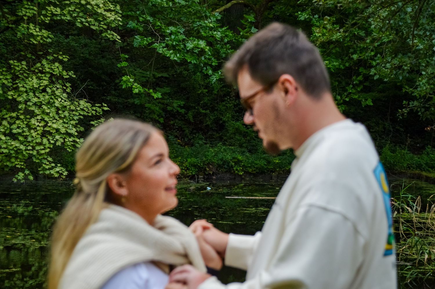 Romantic couple in white shirts sharing an intimate moment in a lush green garden.