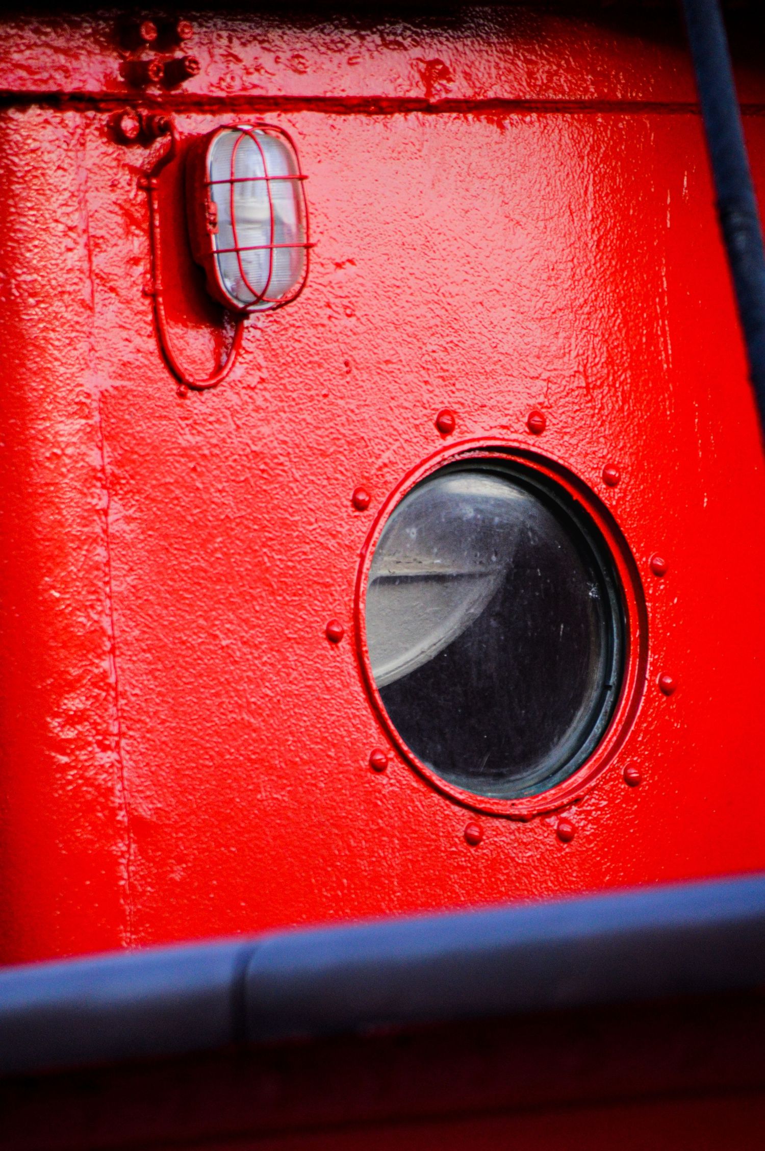 Red painted ship porthole windows in a row creating geometric pattern.