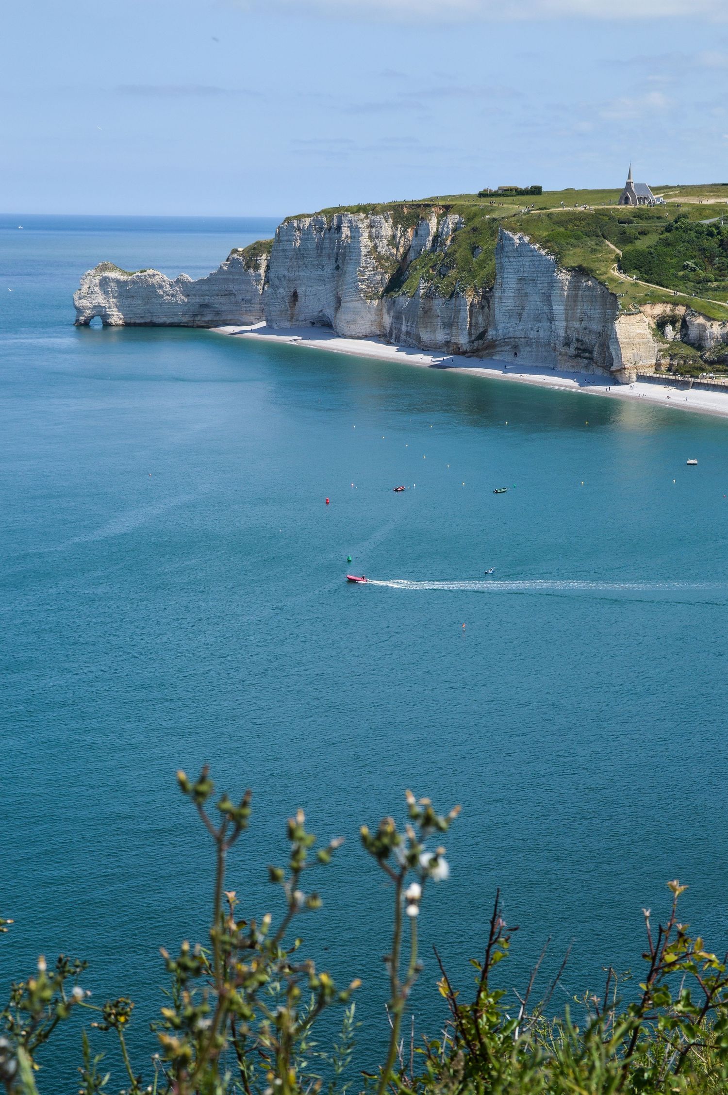 White chalk cliffs of Etretat rise dramatically above turquoise waters along the Normandy coastline.