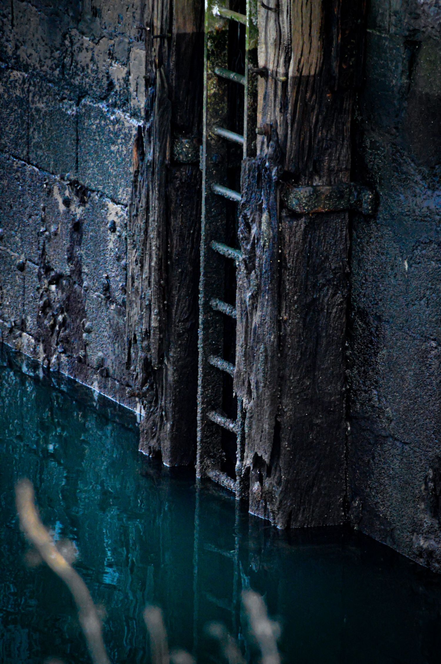 Dark weathered wooden dock wall meets turquoise water.