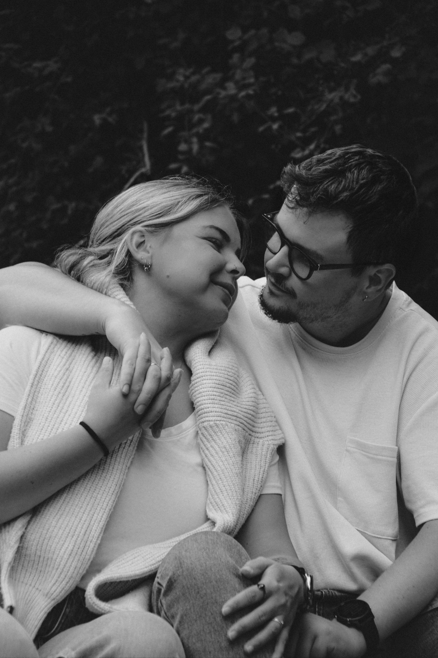 A tender romantic moment between a couple in white sweaters sharing an intimate embrace outdoors.