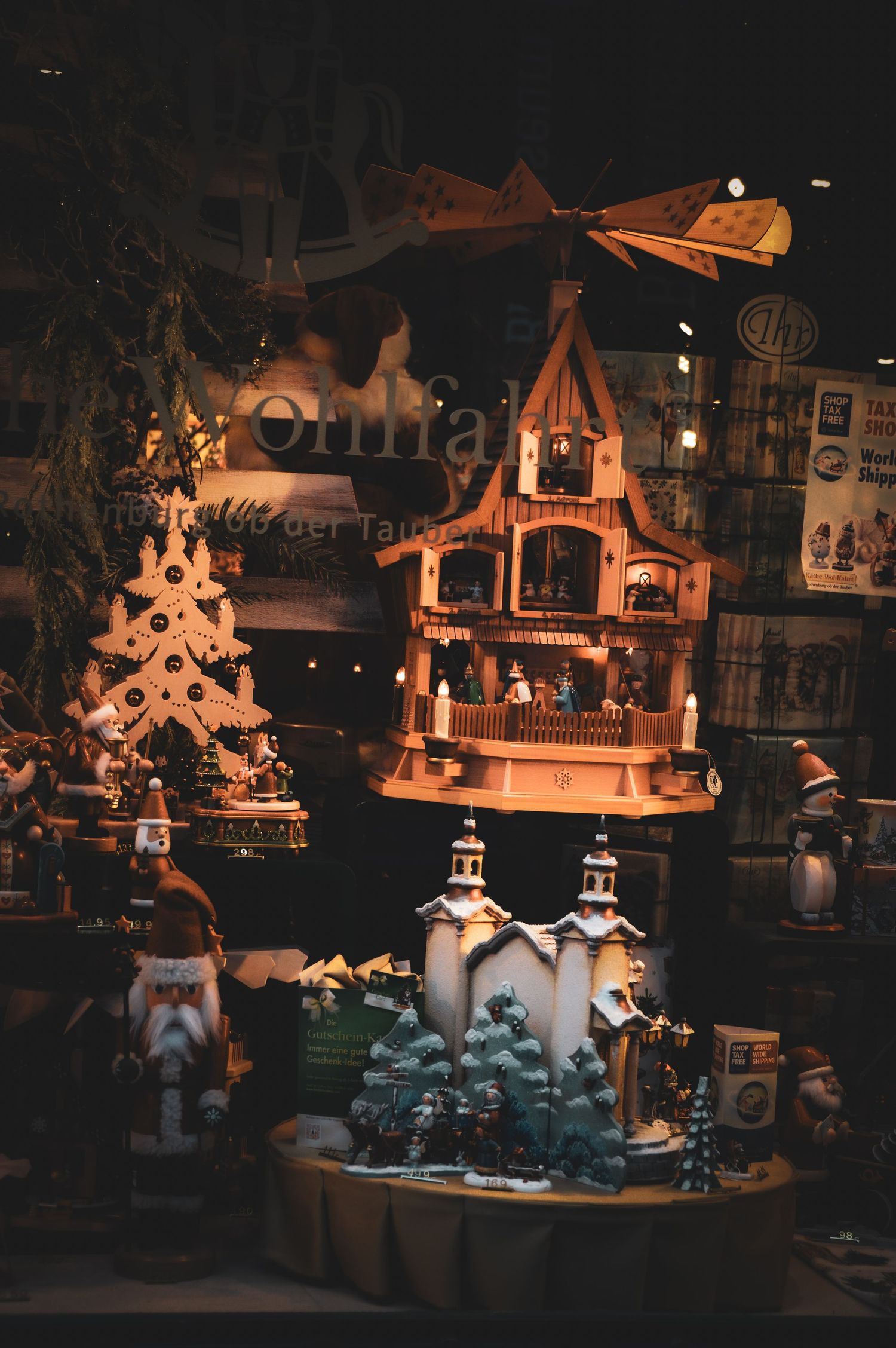 Illuminated Christmas market stalls display glowing winter decorations and ornaments at night.