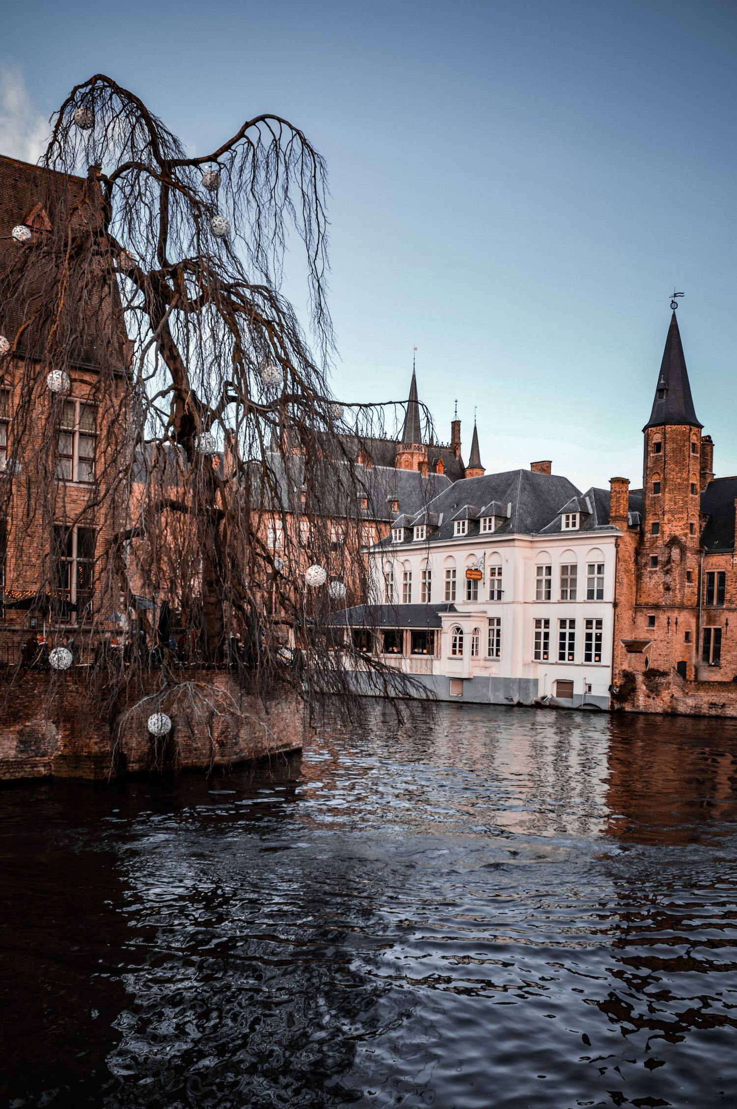 Historic buildings and architecture reflected in canal waters in Bruges, Belgium.