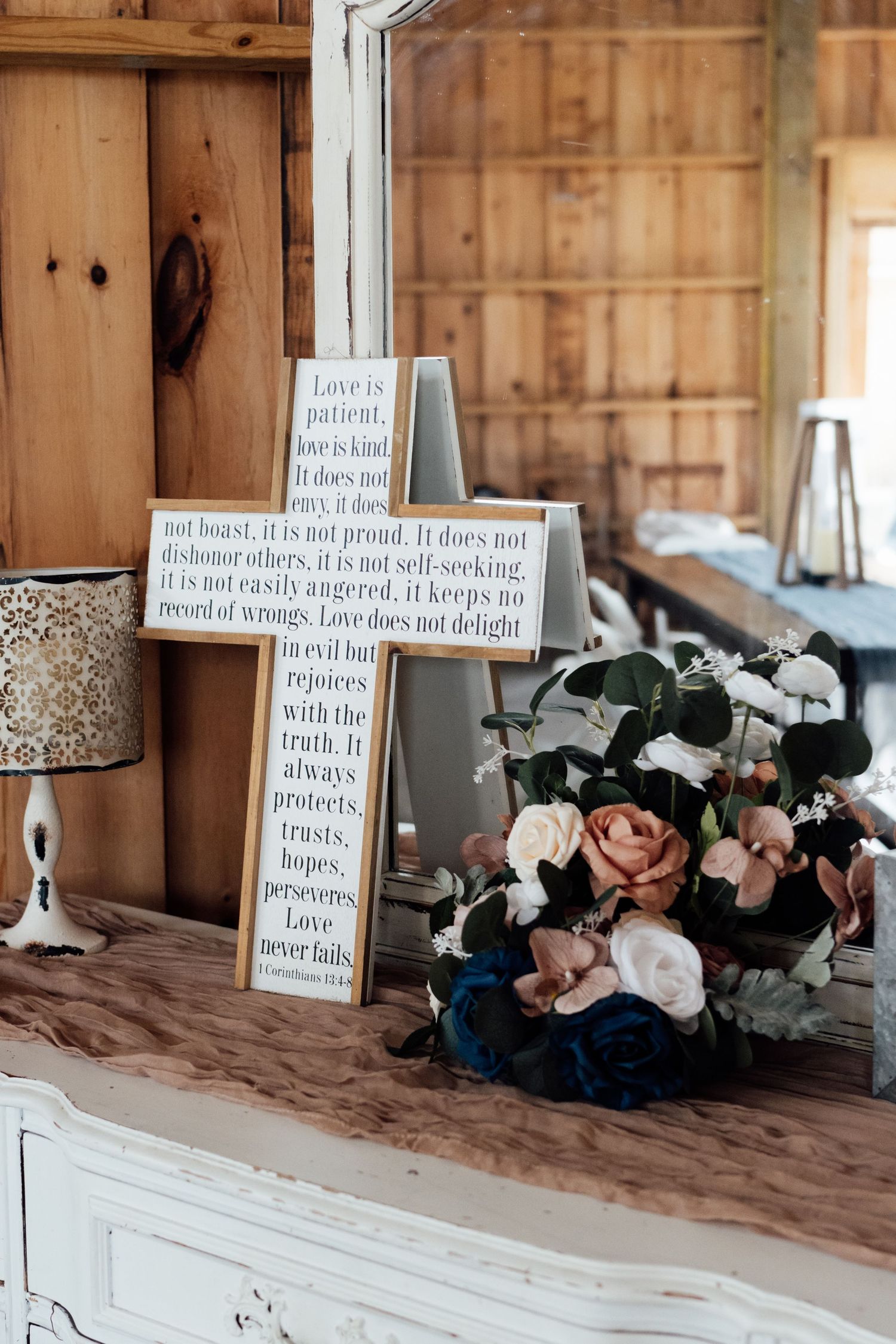 Wedding decor featuring 1 Corinthians 13 love quote sign with pink, navy, and white floral arrangement on white dresser.