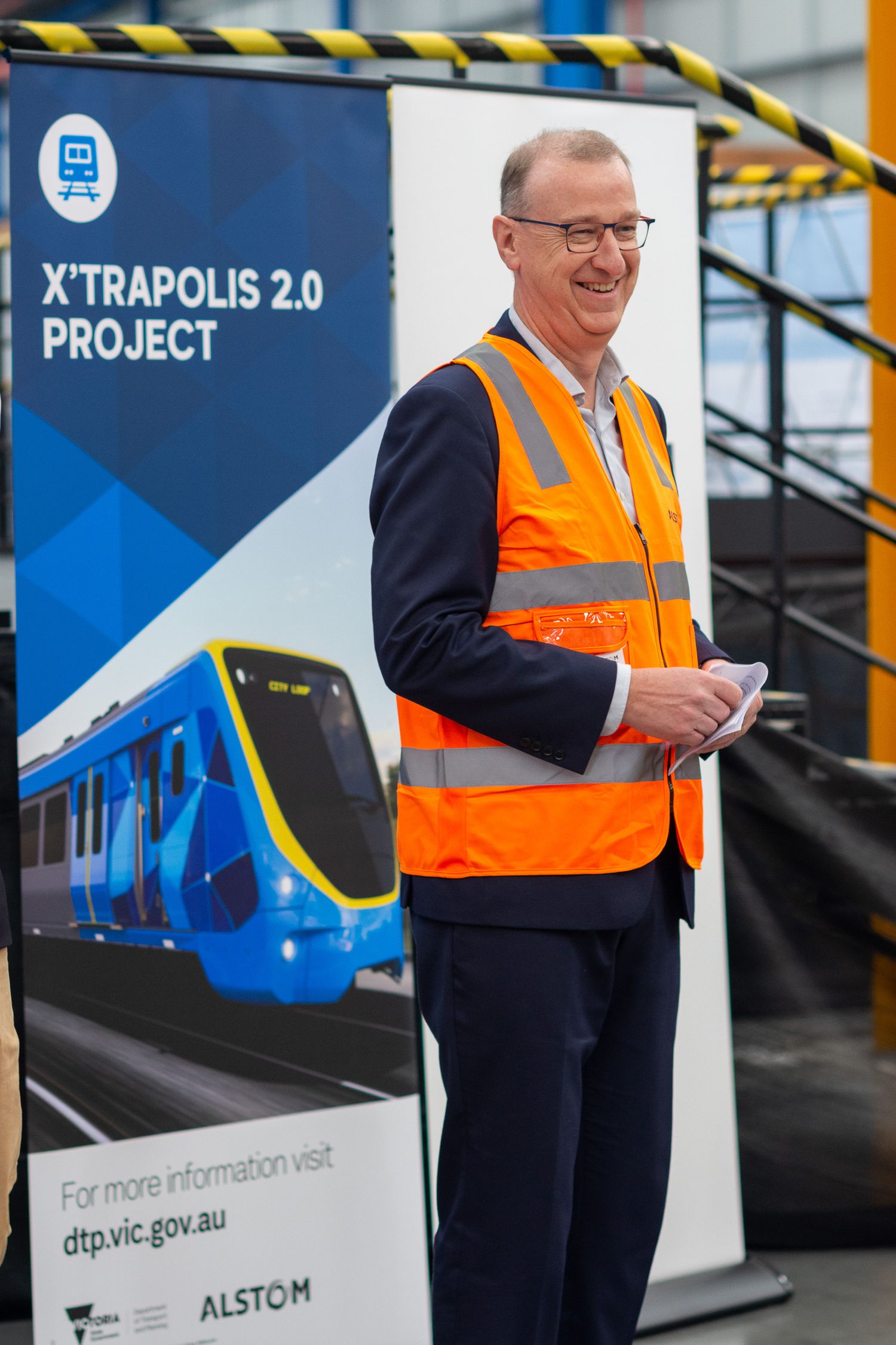 Man wearing an orange high vis vest standing in front of a banner for Xtrapolis 2 Project.