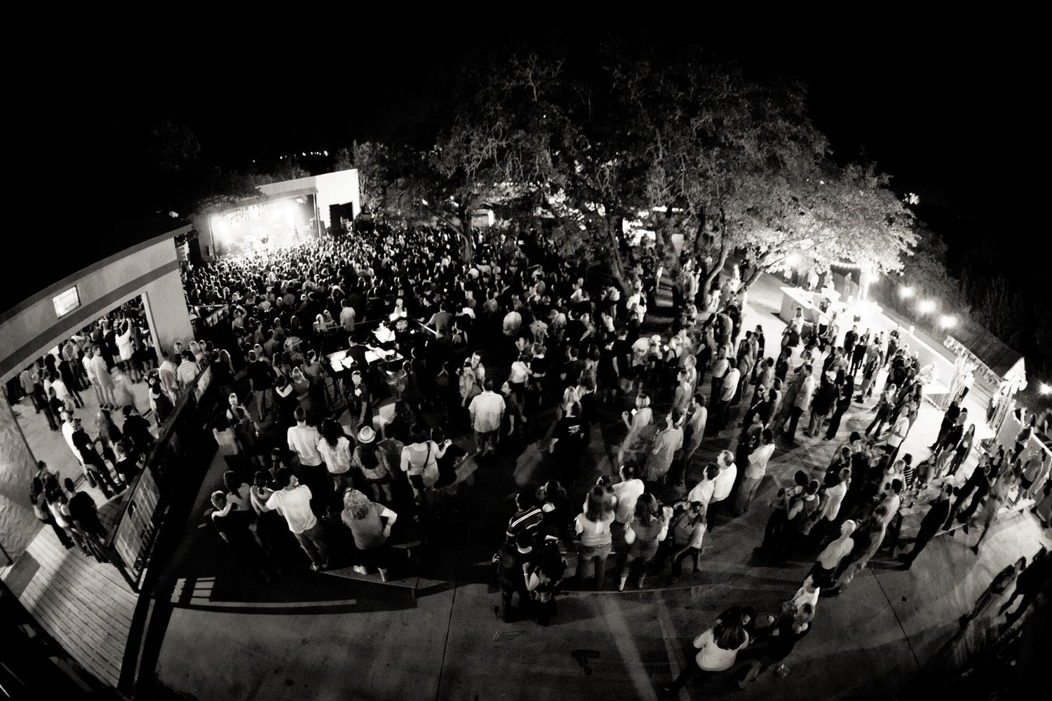 Black and white aerial fisheye photo of a large crowd gathered outdoors at a nighttime event at Josabi's Live in Helotes, Texas.