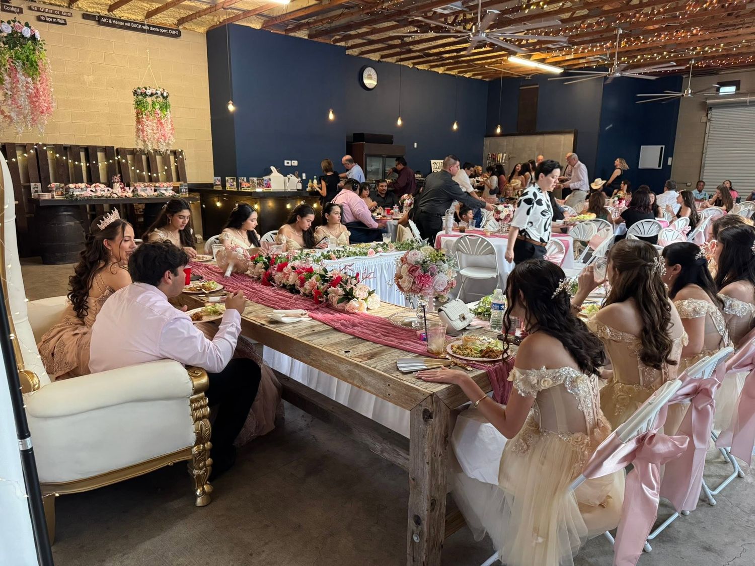 Elegant indoor wedding reception with guests seated at floral-decorated tables in a rustic venue at Josabi's Acres in Helotes, TX.