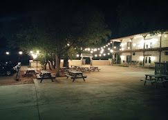 Outdoor patio at night with string lights, picnic tables, and a building at Josabi's Acres in Helotes, Texas