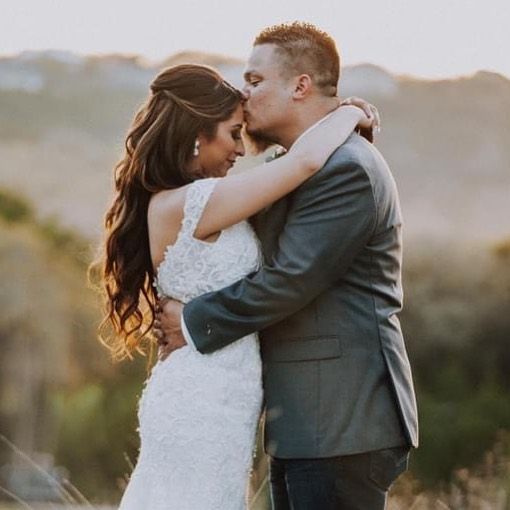 Romantic bride and groom embracing at golden hour with scenic hill country landscape in background at Josabi's Acres in Helotes Texas.