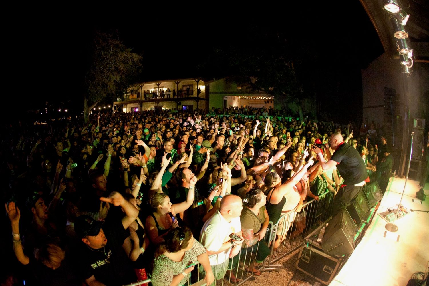 Large outdoor concert crowd at night with hands raised, illuminated stage lights at a packed music festival at Josabi's Live in Helotes TX
