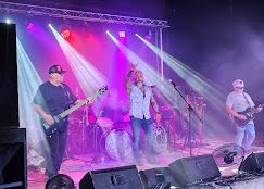 Live rock band performing on stage at Josabi's Live in Helotes, Texas with dramatic lighting, fog effects, and multiple guitar players
