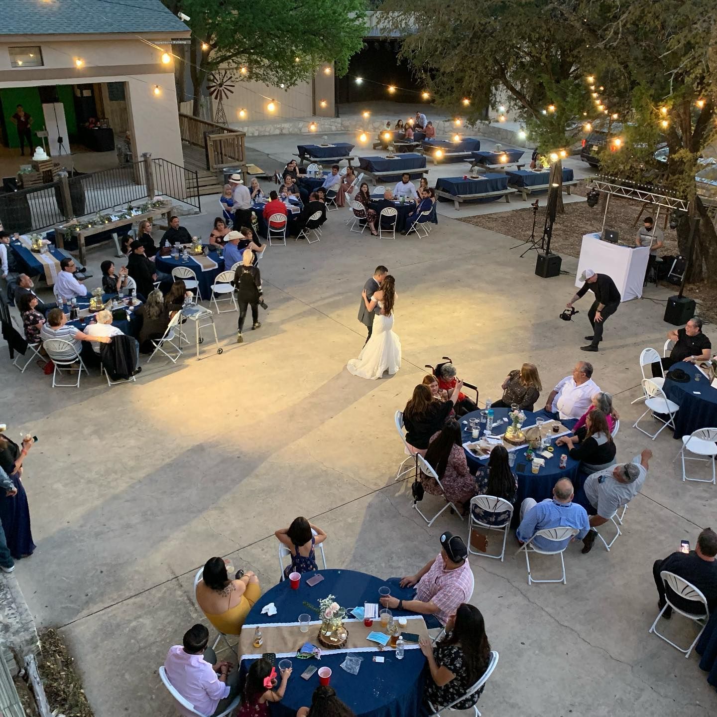 Aerial view of wedding reception with couple sharing first dance surrounded by guests at round tables at Josabi's Acres in Helotes Texas.