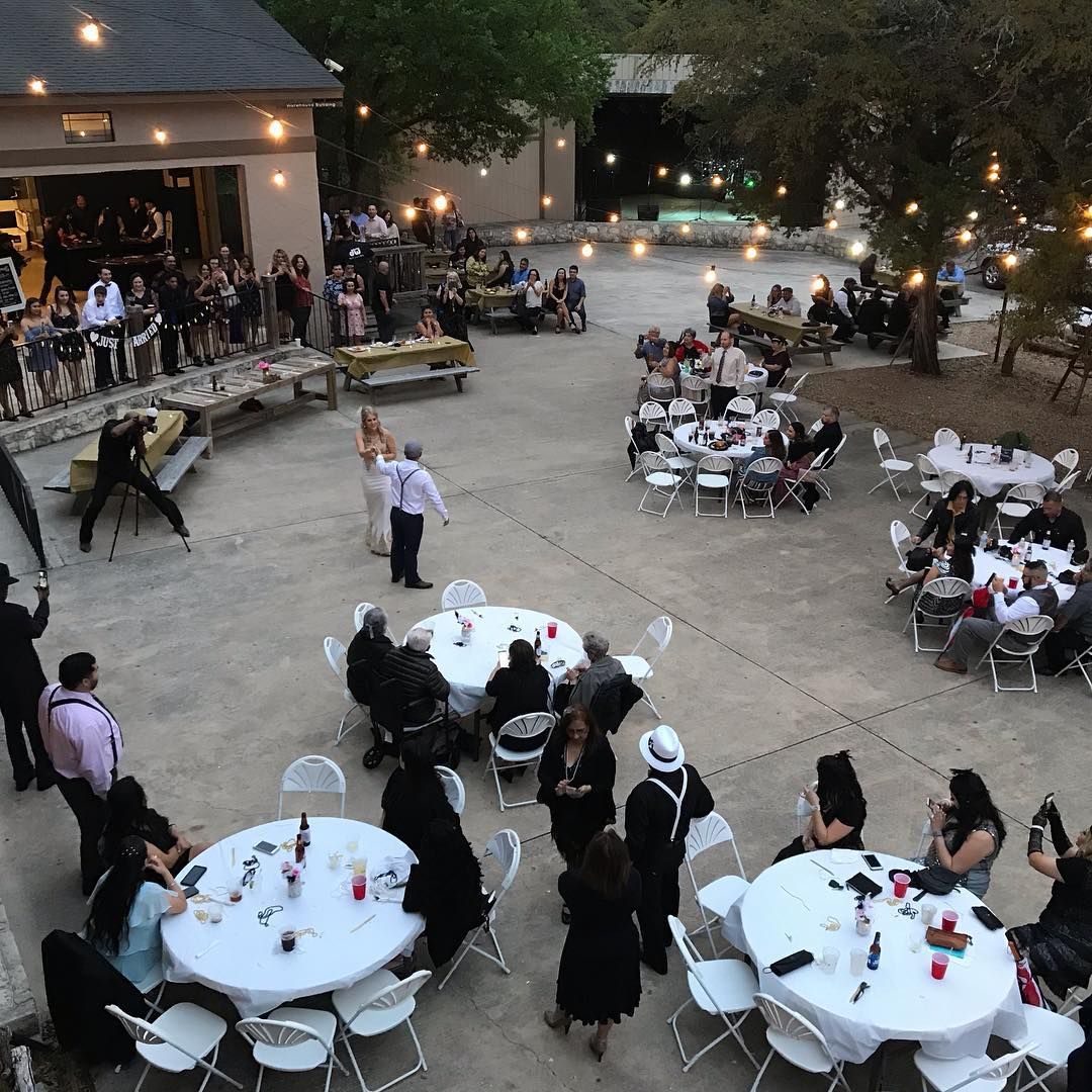 Aerial view of outdoor wedding reception with round white-draped tables, string lights, and guests at Josabi's Acres in Helotes, Texas