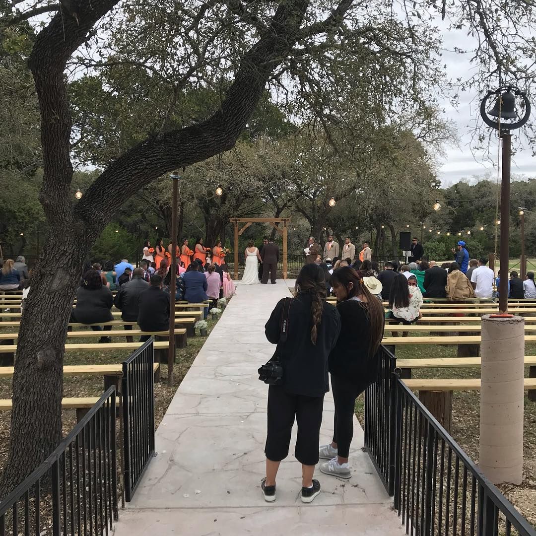 Elegant outdoor dusk wedding ceremony with string lights, wooden benches, and a rustic wooden arch at Josabi's Acres in Helotes, Texas
