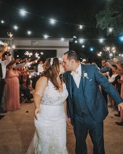 Bride and groom share a kiss during a sparkler send-off at their outdoor evening wedding reception at Josabi's Acres in Helotes, TX.