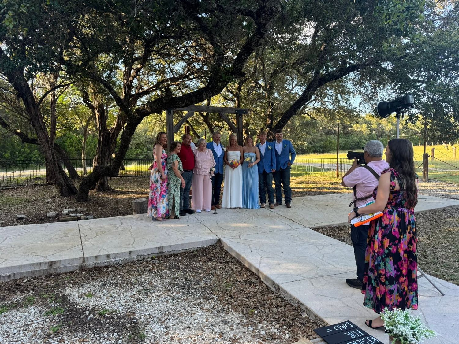 Outdoor wedding ceremony with guests gathered under oak trees on a stone patio at Josabi's Acres in Helotes TX.