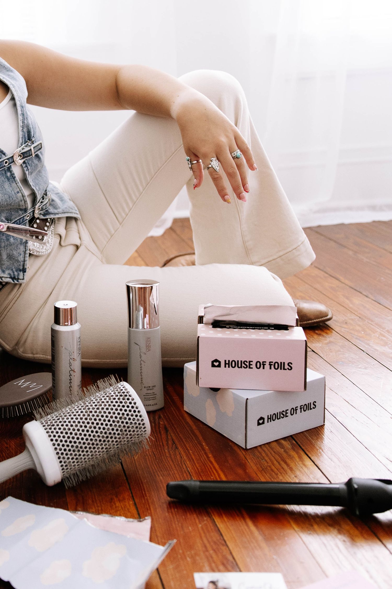 House of Foils hair product boxes with brushes and styling tools arranged on wooden floor.Photography Studio in Bartow Florida.