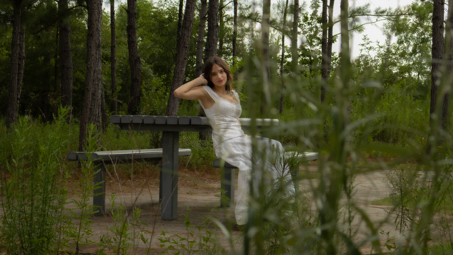 Girl sitting on a bench surrounded by trees