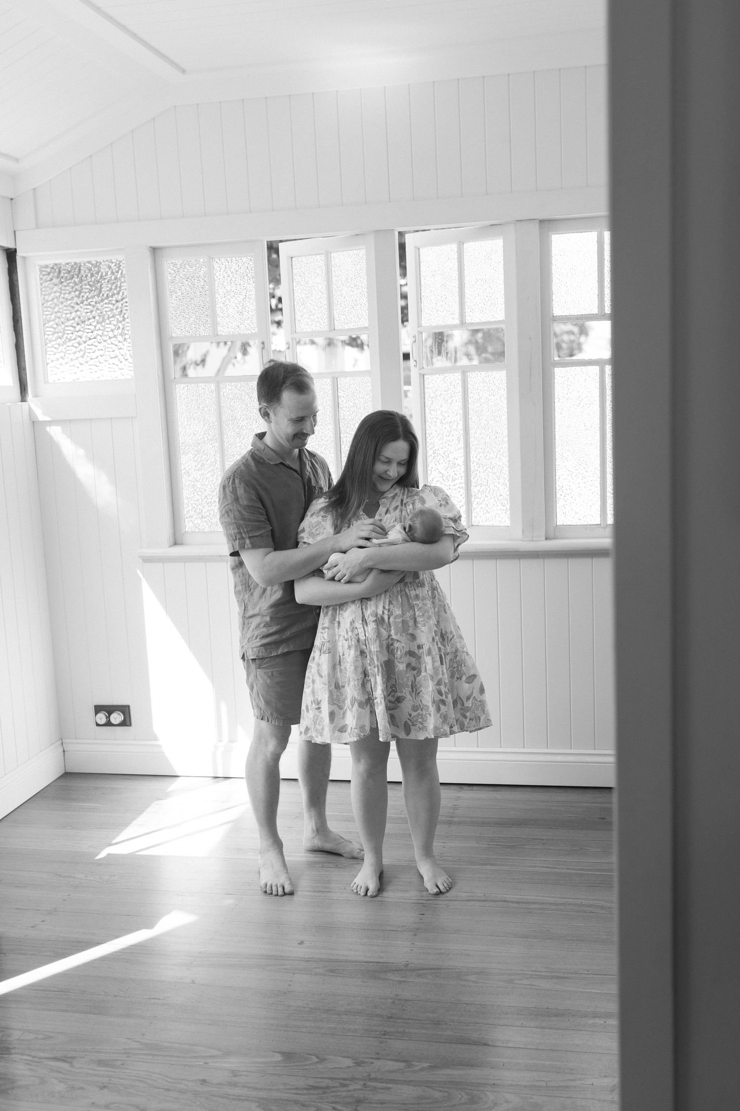 Family cuddling their newborn baby at home