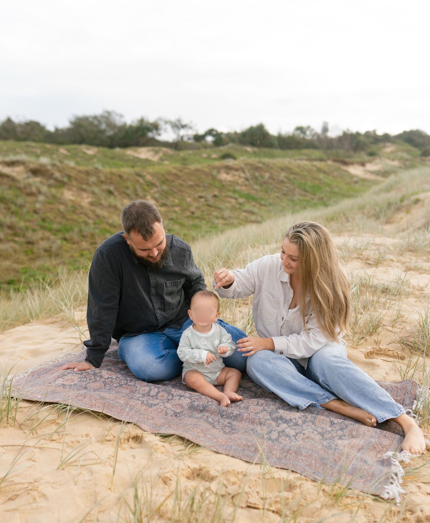 Family of three cuddling together on the beach during a Sunshine Coast family mini photography session