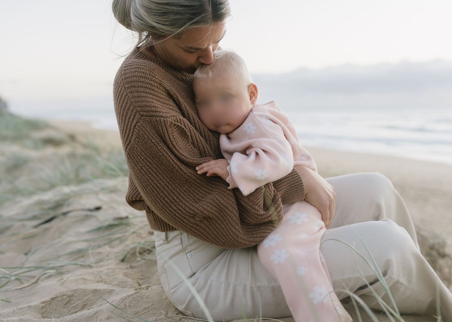 Quiet toddler cuddles between mother and baby at Warana Beach