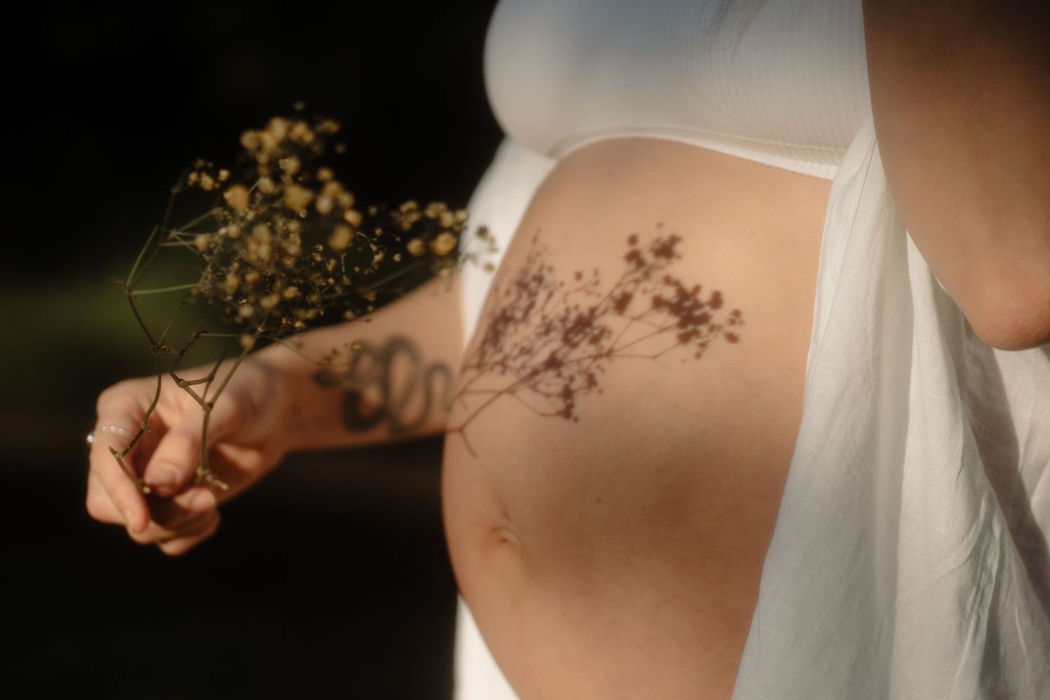 Pregnant mother embracing her baby bump during a relaxed maternity photography session