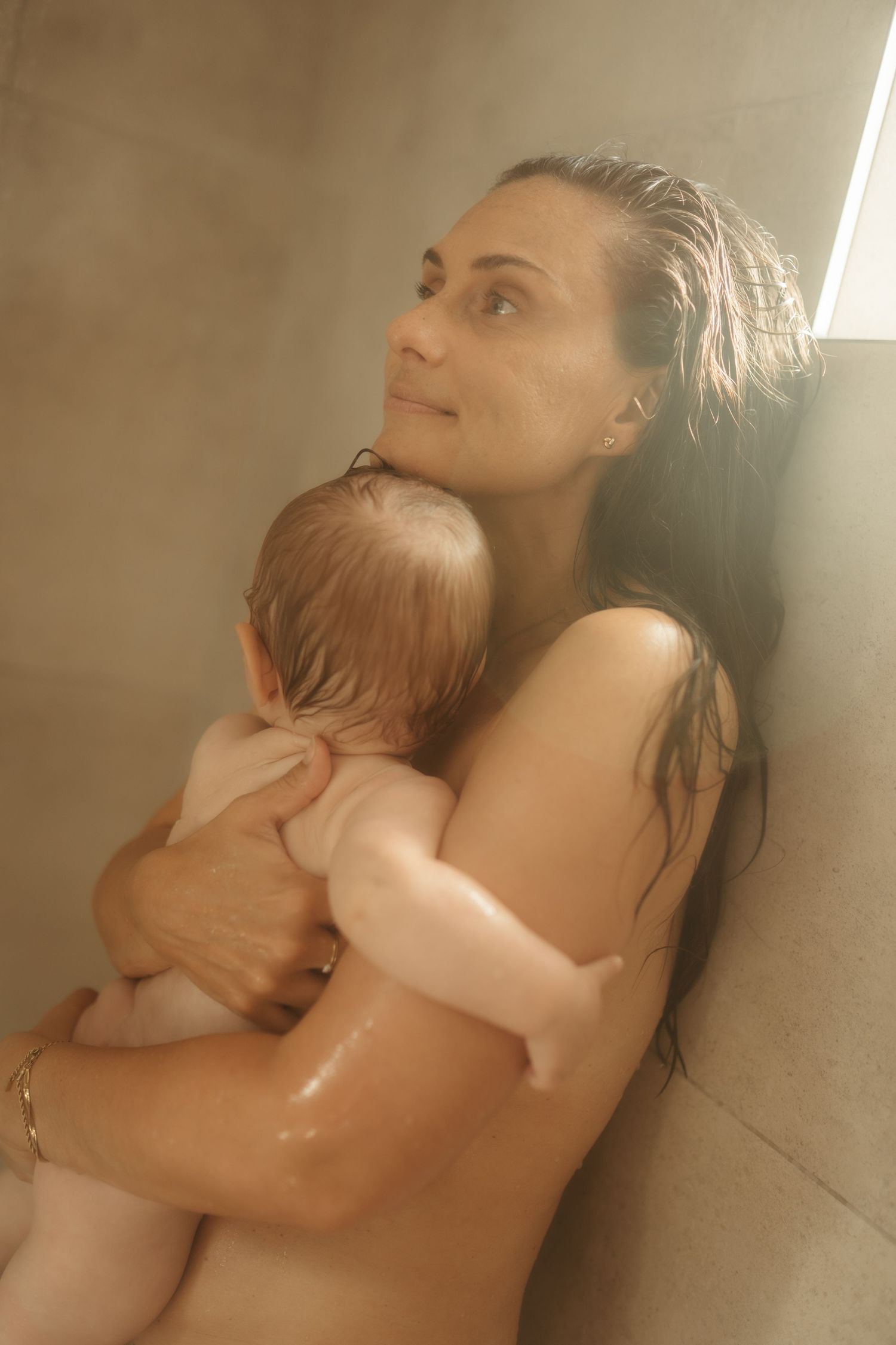Mother and baby sharing a quiet cuddle in the shower during a heartfelt motherhood session