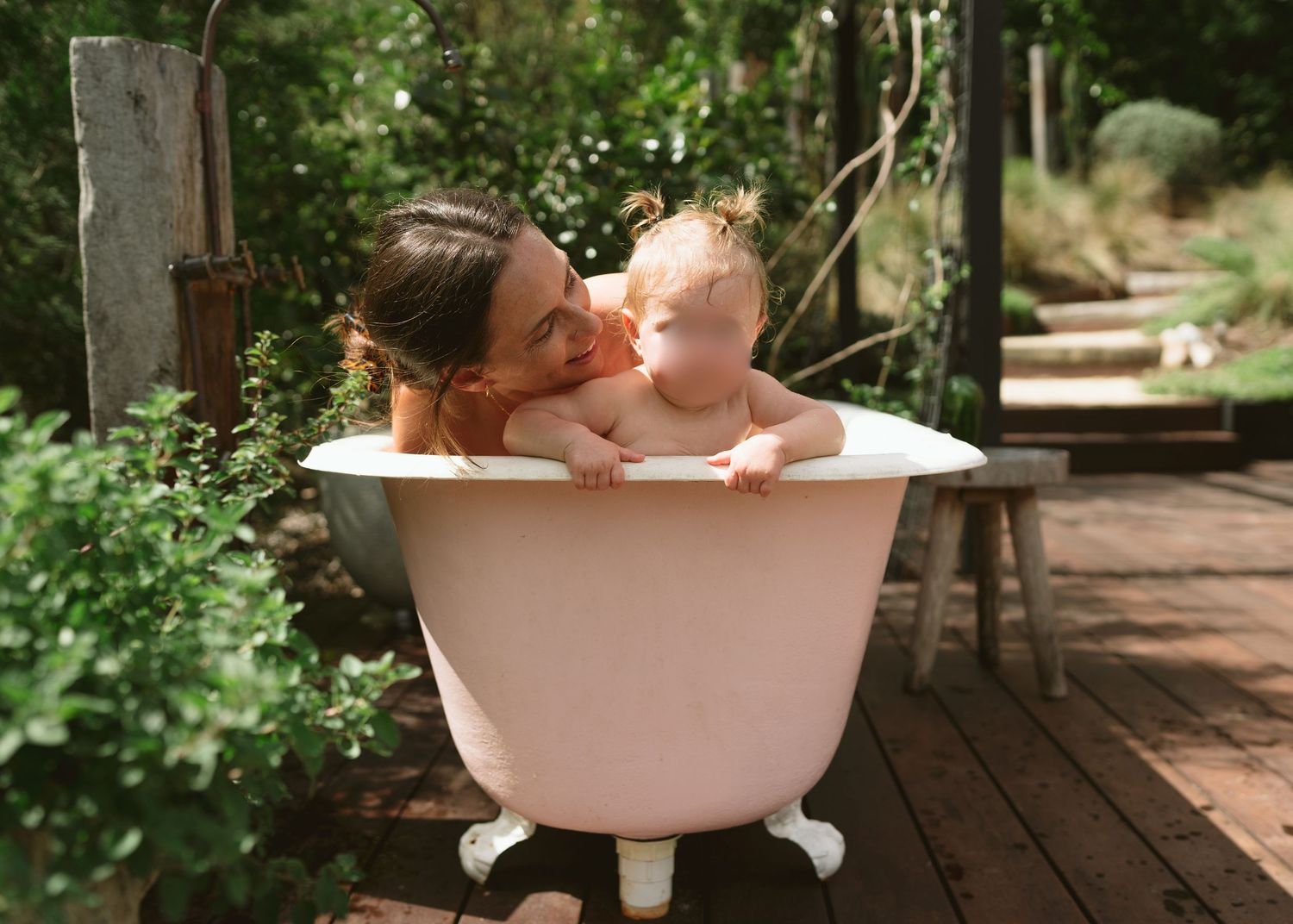 Mother sharing a joyful bath time moment with her toddler outdoors