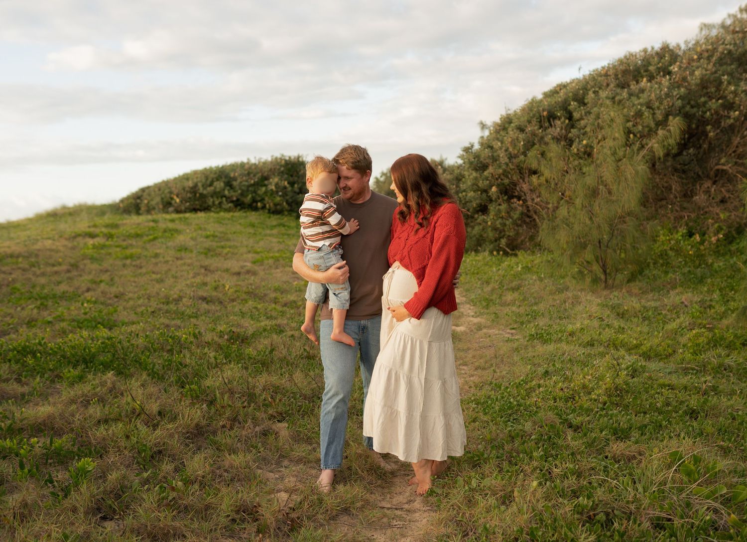 Family of three playing together on the beach during a Sunshine Coast family and maternity photography session