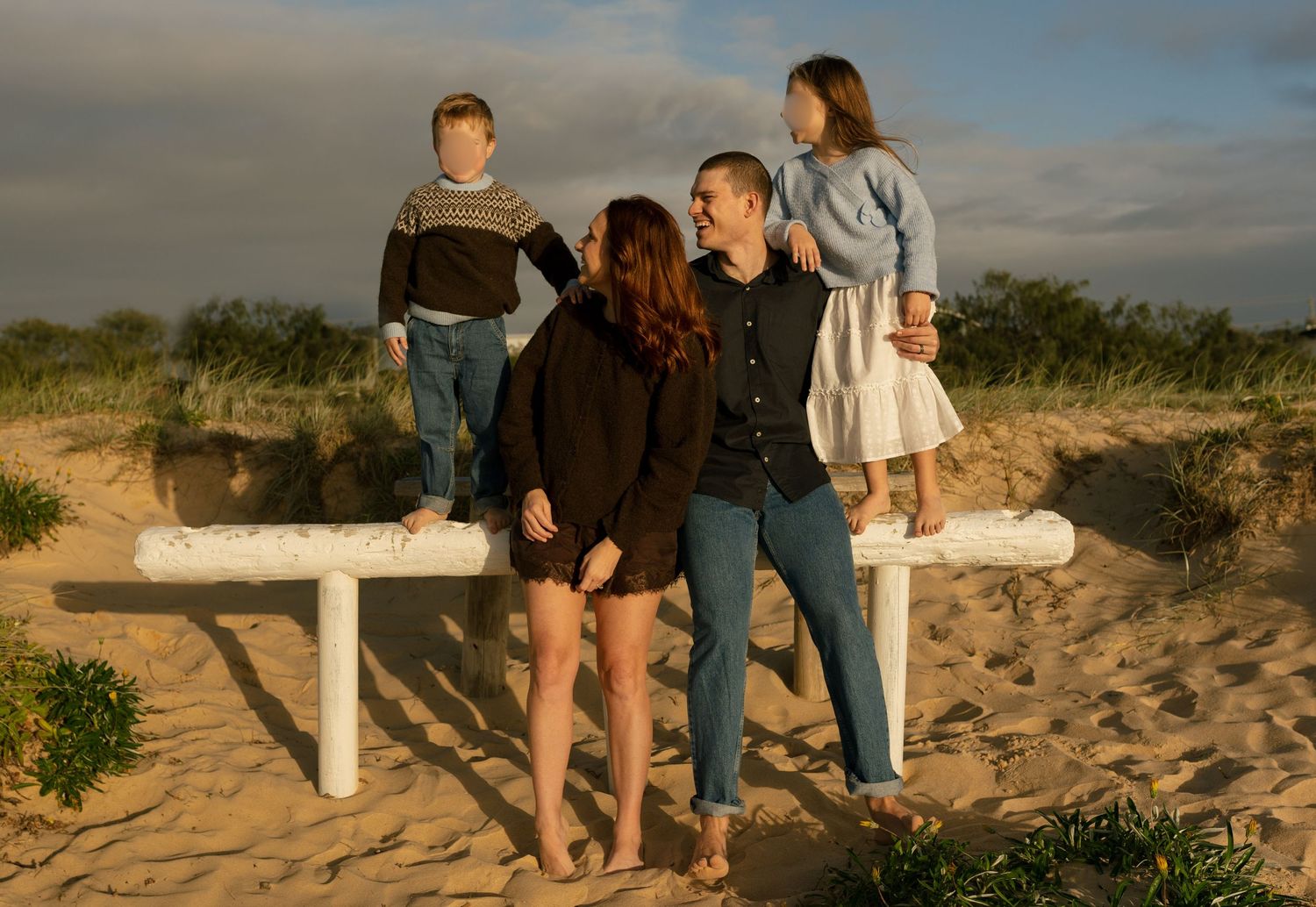 Family laughing together while walking along Warana Beach at sunrise