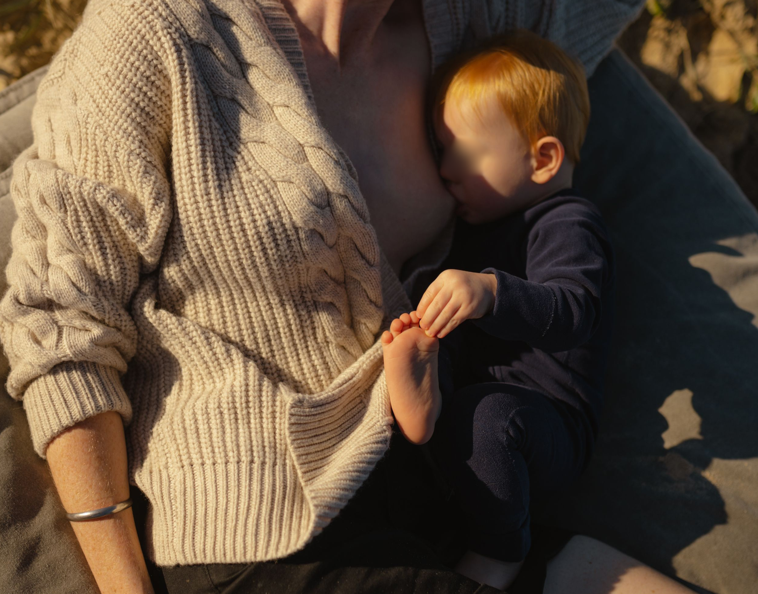 Mother breastfeeding child at the beach at an early morning warana mini session