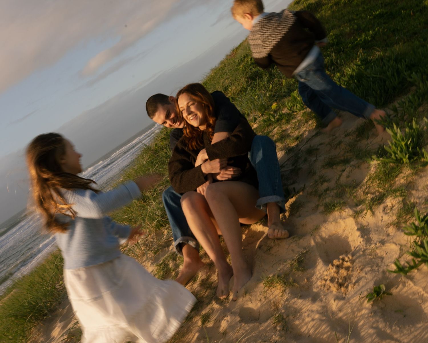 Family laughing together while playing along Warana Beach at sunrise