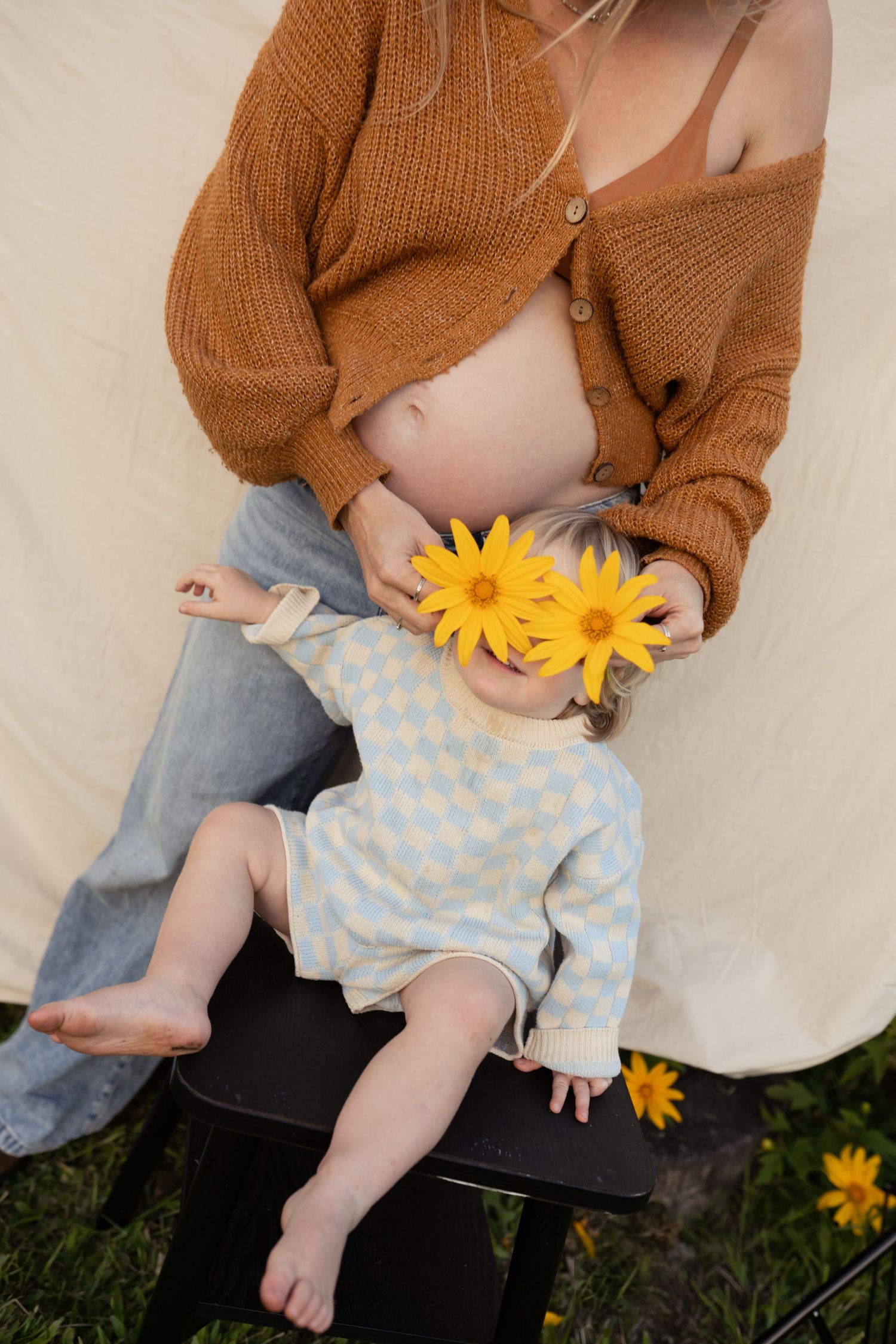 Pregnant mother playing with her toddler in a field with flowers