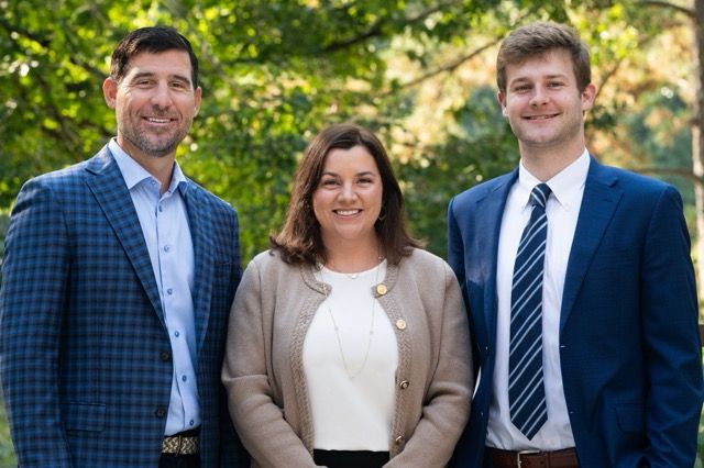 Outdoor corporate team portrait of three business professionals standing together in business attire