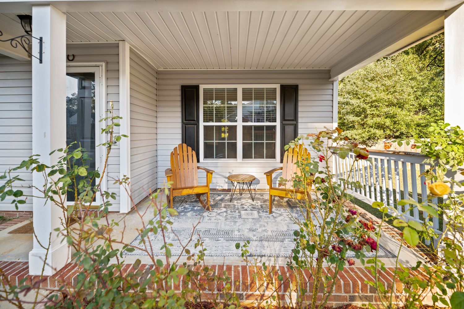 A charming white porch with wooden rocking chairs and colorful fall decorations creates a welcoming Fayetteville home in North Carolina