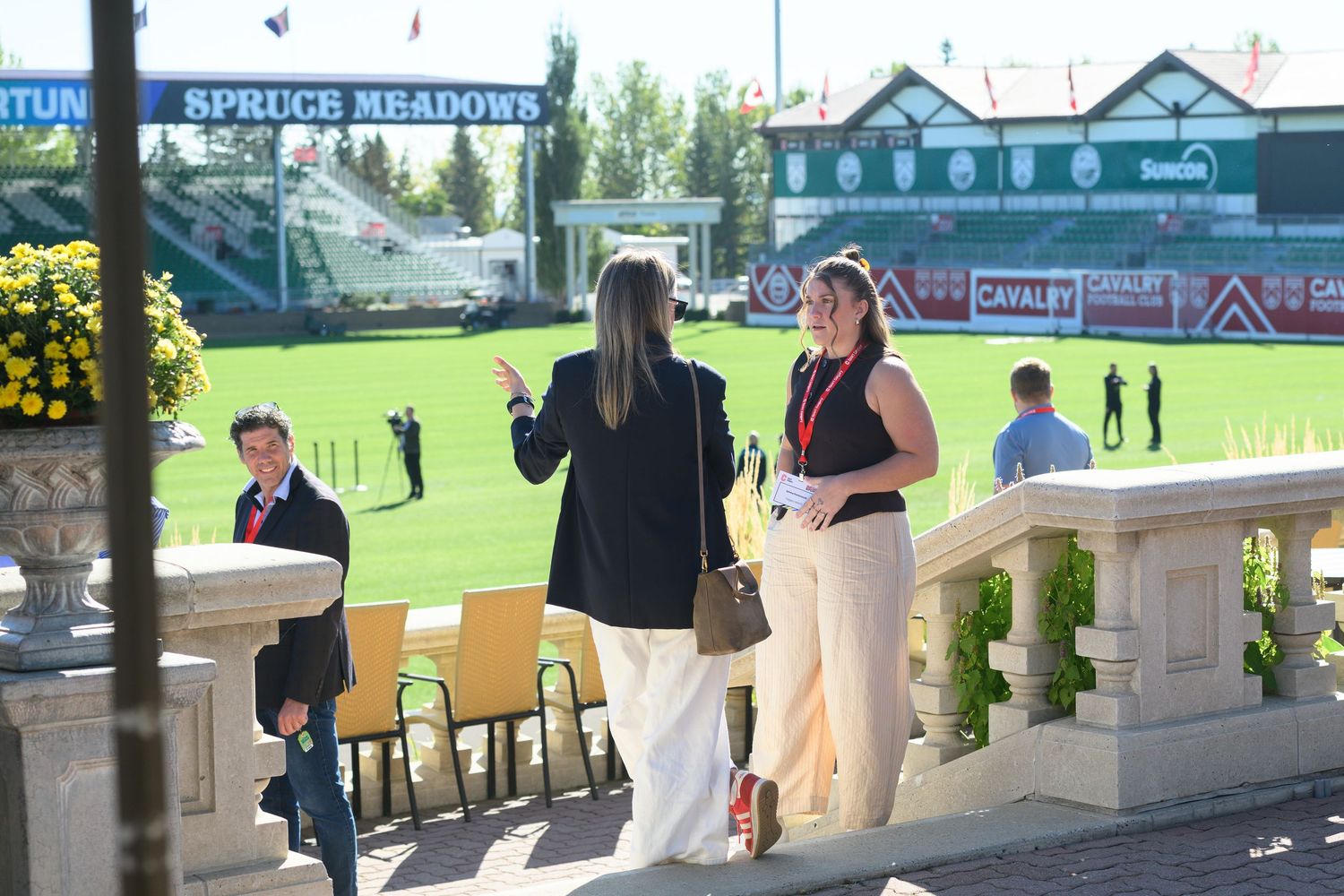 Two women networking outdoors at Spruce Meadows equestrian venue on a sunny day.