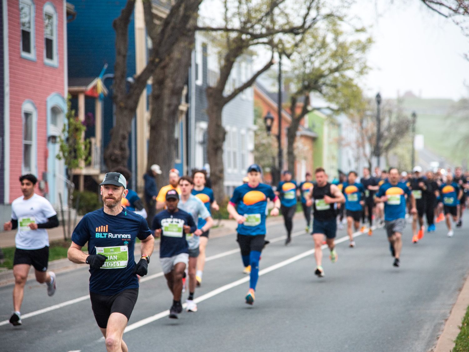 Runners competing in a road race through a colorful historic town street during a spring marathon event.