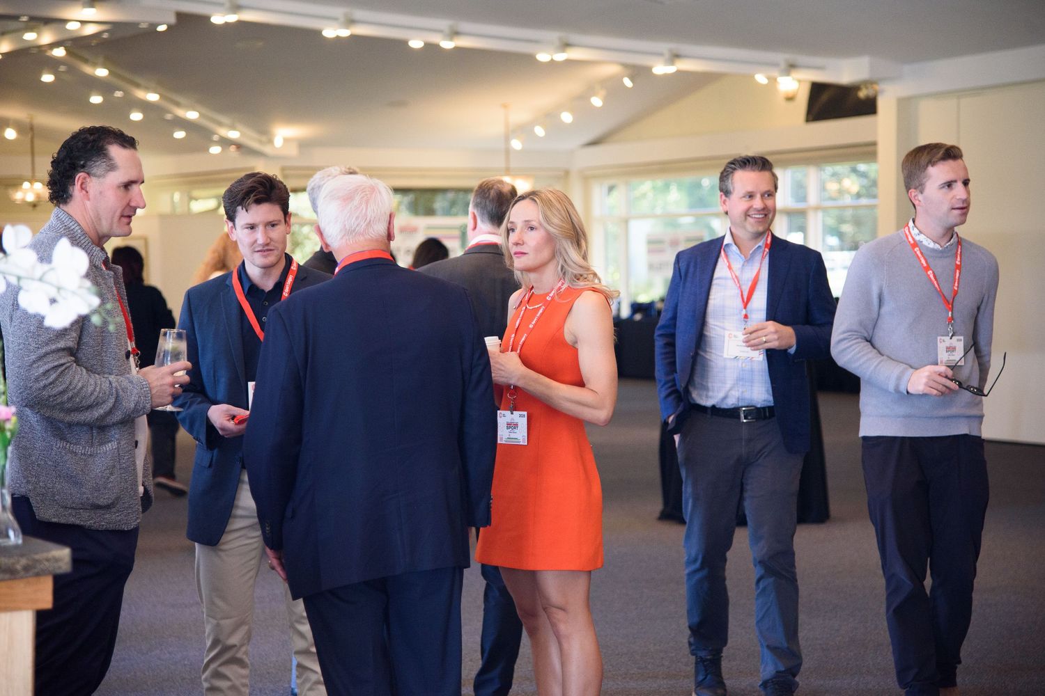 Group of professionals in business casual attire mingling at an indoor corporate networking event.