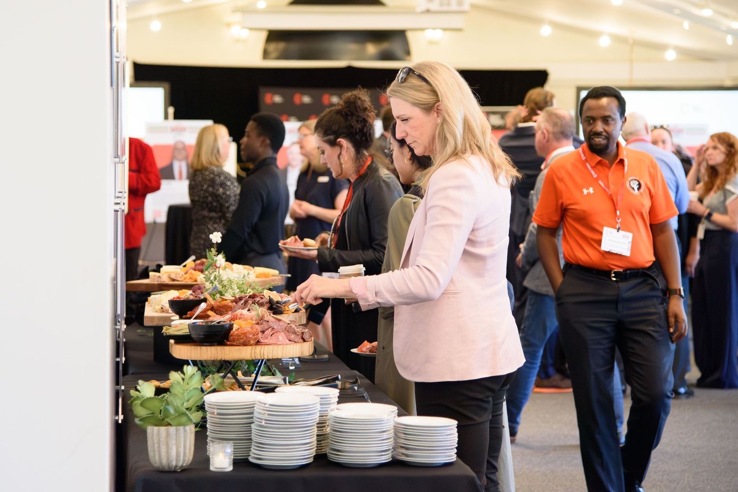 Guests serving themselves at a buffet table during a catered corporate event with white plates and fresh food displays.