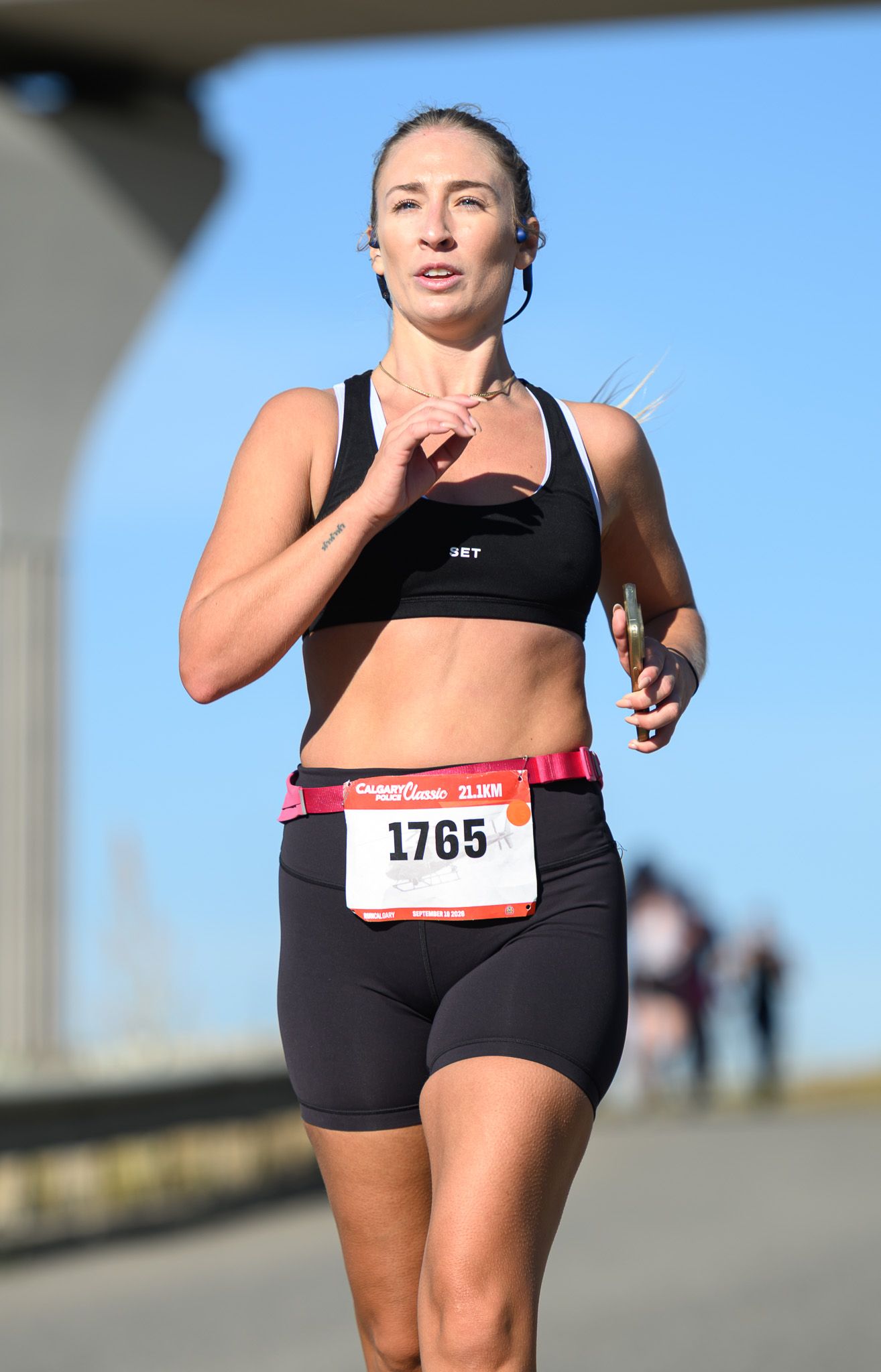 Female runner wearing bib number 1765 competing in an outdoor road race on a sunny day.