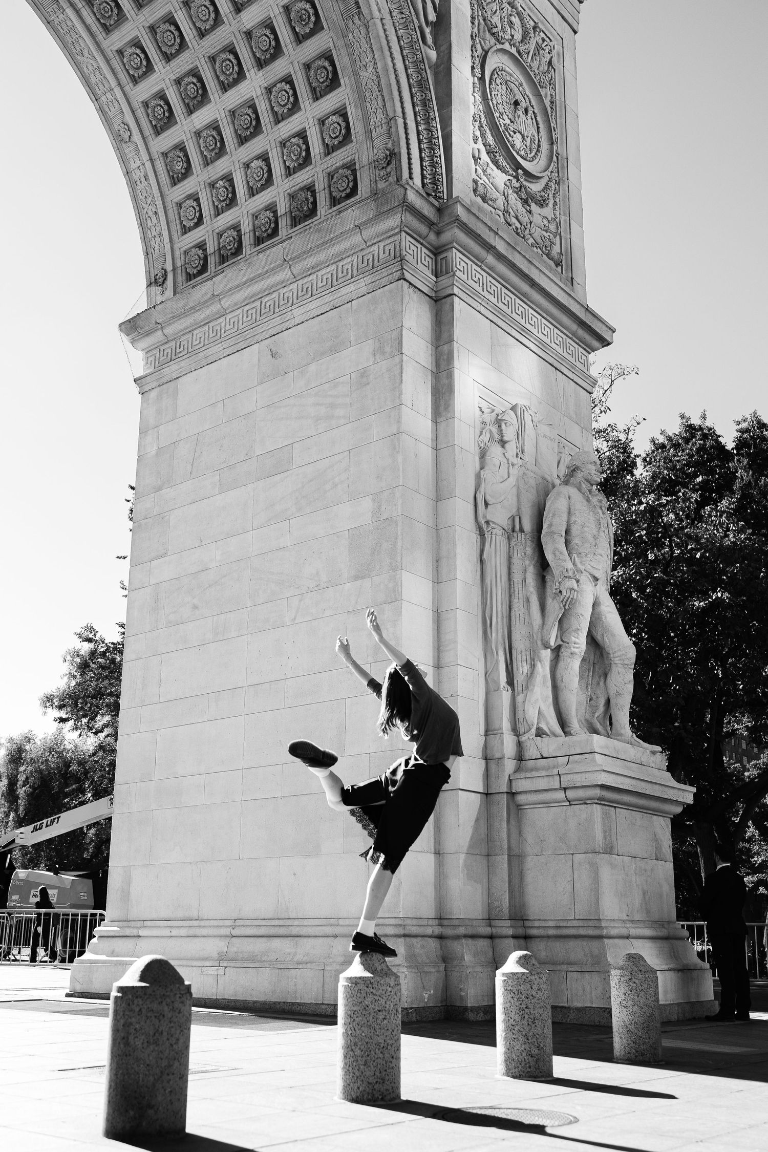 Black and white photo of a dancer leaping in front of the Washington Square Arch in New York City.