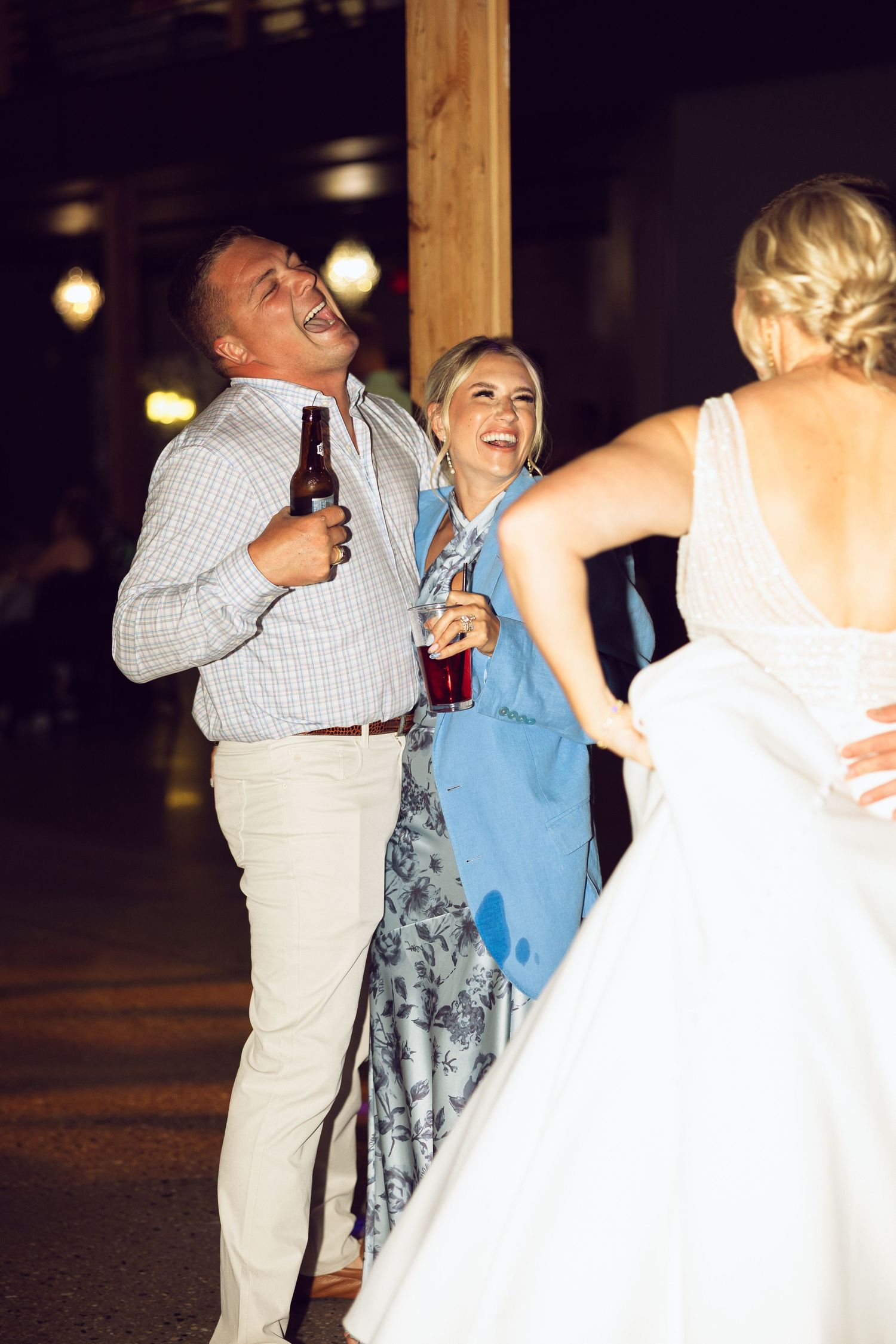 Wedding guests laugh and celebrate on the dance floor while the bride in a white gown dances in the foreground.