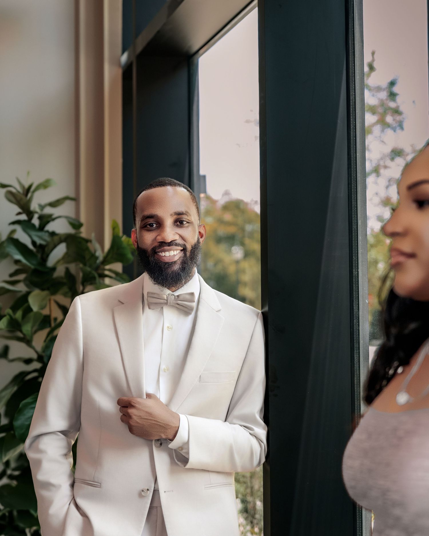Man in a white suit smiling beside his partner during an elegant couple portrait session