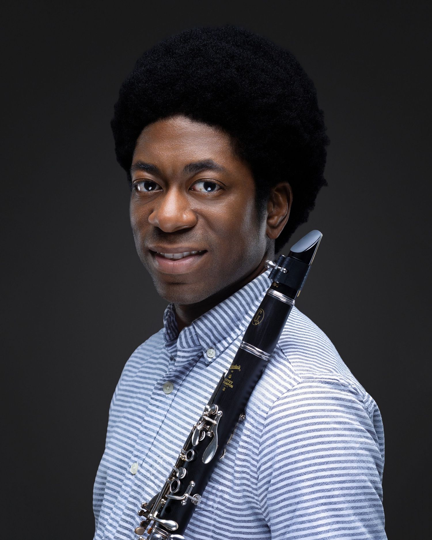 Professional portrait of a musician holding a clarinet against a dark studio background